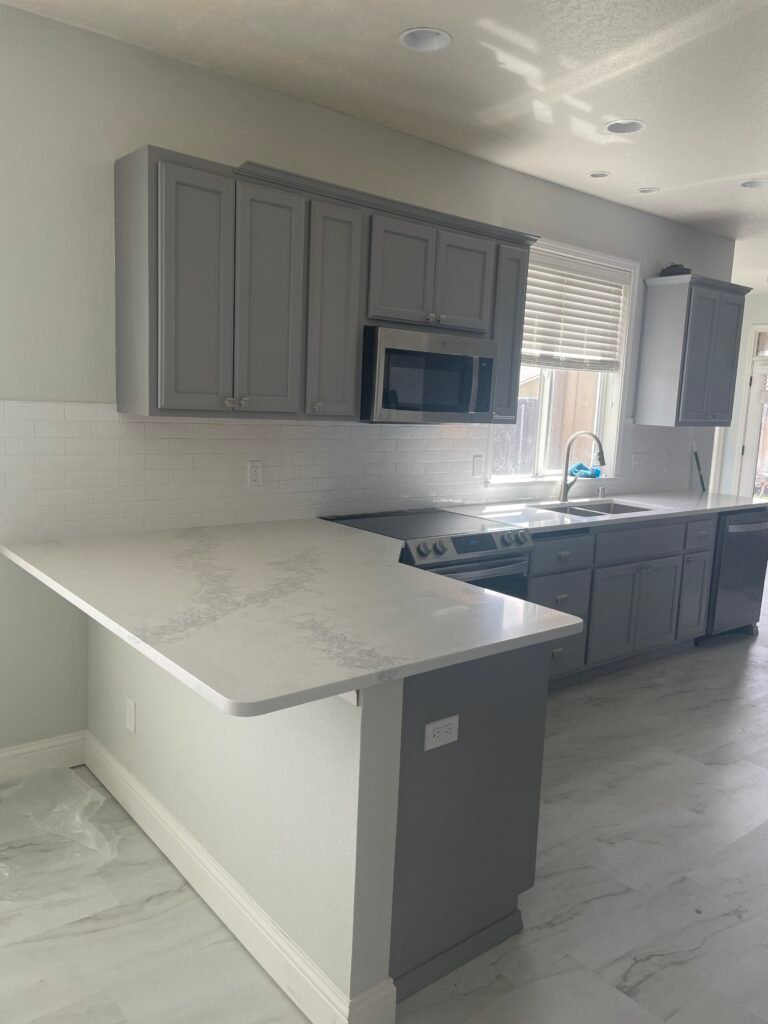Modern kitchen remodel featuring custom gray cabinets, quartz countertops, subway tile backsplash, and luxury flooring completed by Barean Hilu LLC in Benton County, Washington.